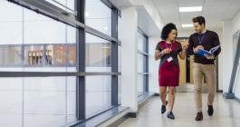 two people walking down a hallway talking