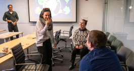 Candid photo of four teachers in a classroom setting playing charades. A screen in the background says "climate change charades."