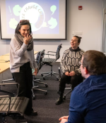 Candid photo of four teachers in a classroom setting playing charades. A screen in the background says "climate change charades."